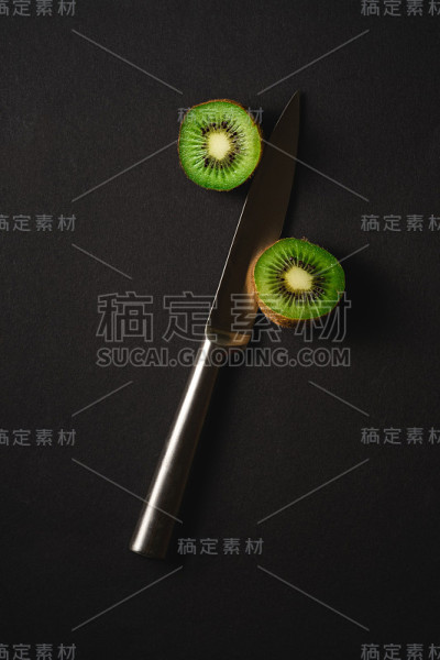 猕猴桃用菜刀切成半片，背景为黑色，拷贝空间，俯视图