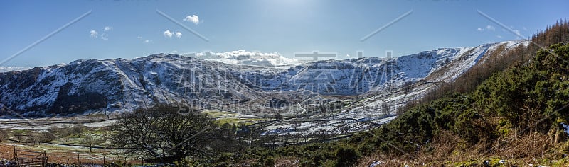 在雄伟的蓝天和灿烂的阳光下，雪山峡谷与山脉斜坡的全景风景