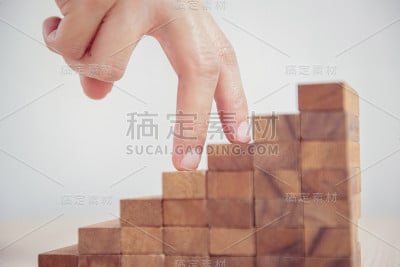 女人手扶着他的手指走上通往成功和渴望的木制台阶。