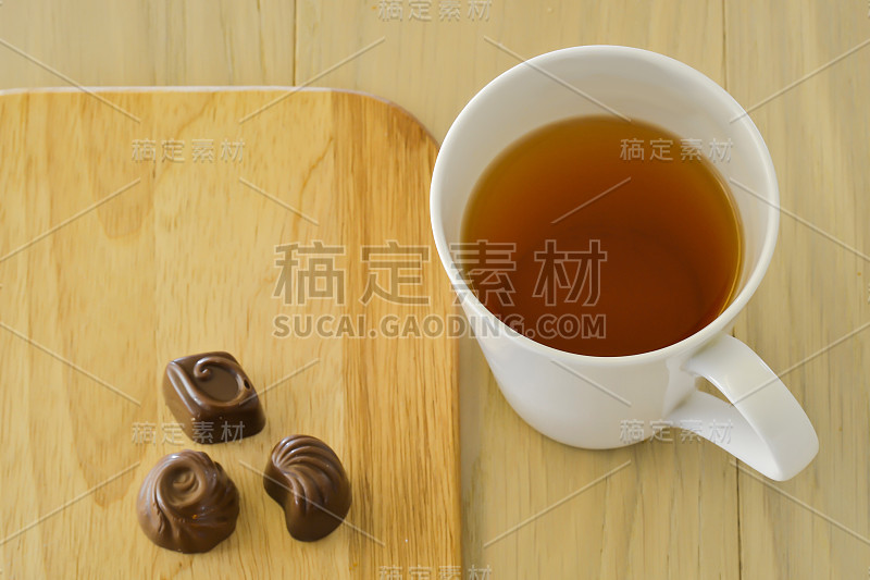 木桌上放着茶杯和三个巧克力糖果