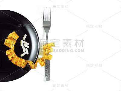 用叉子和卷尺将白色药丸放在黑色盘子上