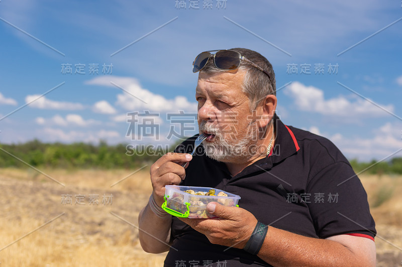 白种人大胡子老人在户外吃蒸蔬菜的肖像