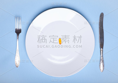 一颗药丸放在餐盘上，餐具在蓝色背景上