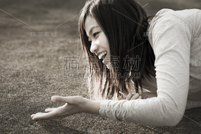 一名年轻的日本女子愉快地伸出手，躺在地上笑着。