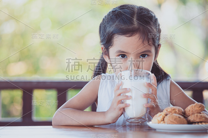 可爱的亚洲小女孩正在喝牛奶与饼干的早餐