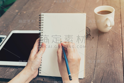 近一点，女人在木桌上写笔记本。