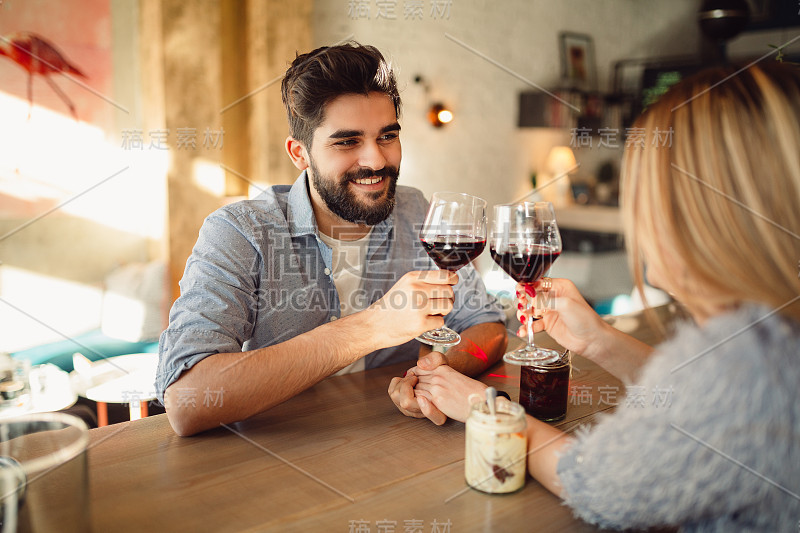 浪漫的情侣用红酒碰杯庆祝情人节或纪念日。