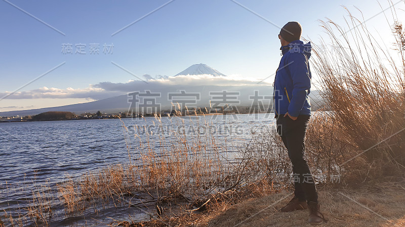 日本——一名男子站在川口湖边，眺望富士山