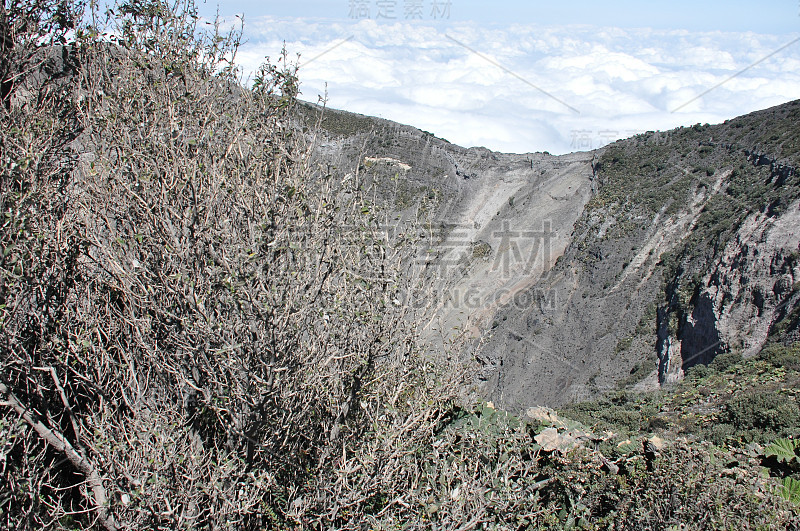 哥斯达黎加的伊拉祖火山。有防护屏障的云层中的火山口。熔岩和浮石的碎片。