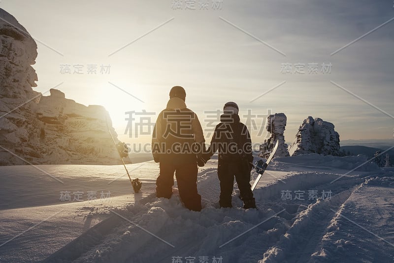 带着滑板的滑雪者在冬季的高山和悬崖上自由行走。轮廓上的日落