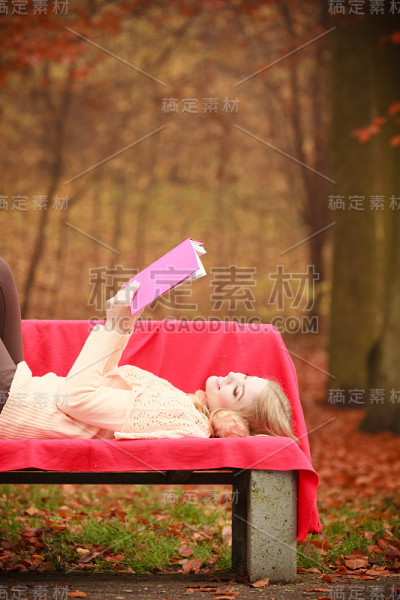 金发女孩与书在秋天公园