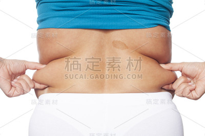 胖女人手牵着肚子上过多的脂肪。保健和女性饮食生活理念，以减少腹部和塑造健康的腹部肌肉。