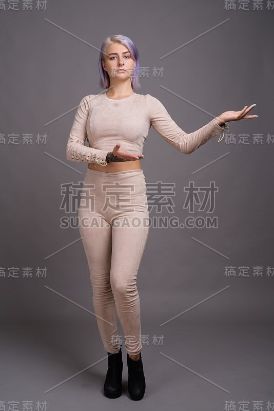 工作室拍摄的年轻美丽的叛逆女子与彩色的头发与灰色的背景