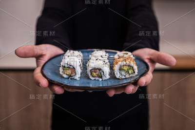 男厨师在厨房里拿着蓝色的寿司卷。