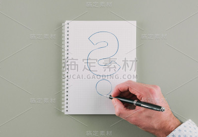 手拿圆珠笔在螺旋记事本上画问号