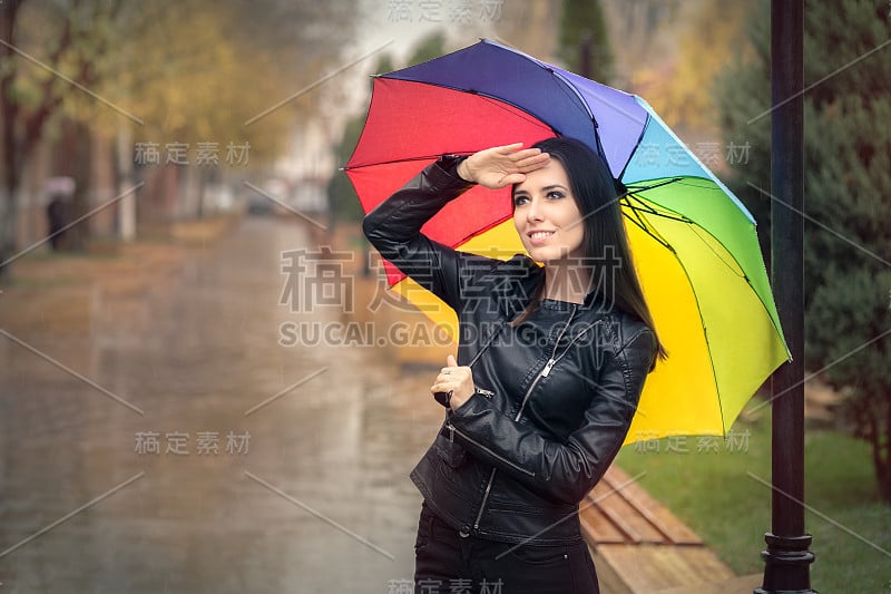 快乐的秋天女人拿着彩虹伞检查下雨