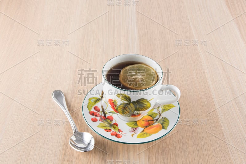 木桌上放着一杯茶和一茶匙茶