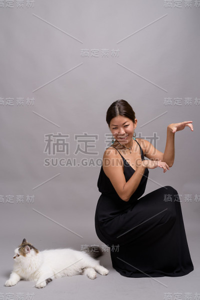 摄影室拍摄的年轻亚洲女性穿着正式的黑色连衣裙，背景是灰色