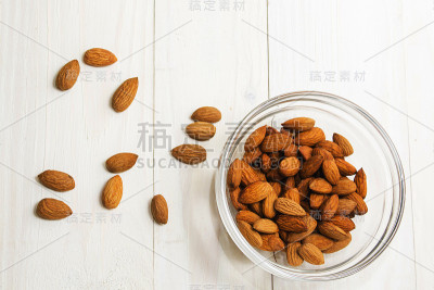 玻璃容器里放很多杏仁，背景是浅色的木头。