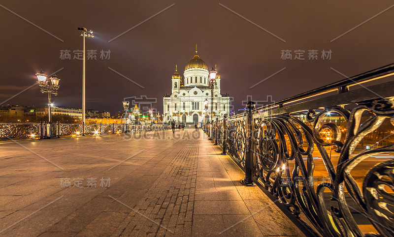 莫斯科东正教教堂的广角夜景灯，金色的圆屋顶和黑色的金属栅栏的桥和水的倒影