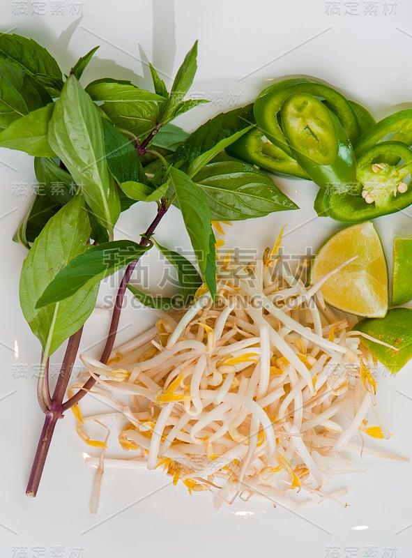 越南河粉汤配菜。豆芽，罗勒叶，墨西哥辣椒，青柠片，红洋葱和香菜。经典的传统越南，中国或泰国餐厅的河粉