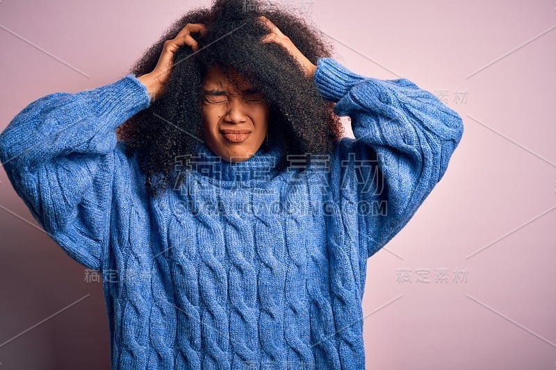 年轻美丽的非洲裔美国女人与非洲发式穿冬季毛衣在粉红色的背景遭受头痛绝望和压力，因为疼痛和偏头痛。手放