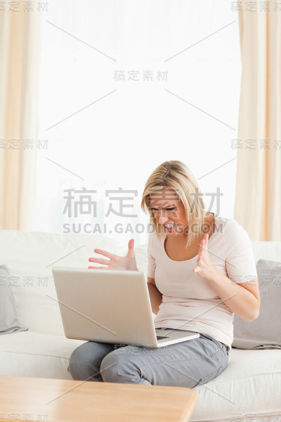 一个心烦意乱的金发女人在用笔记本电脑