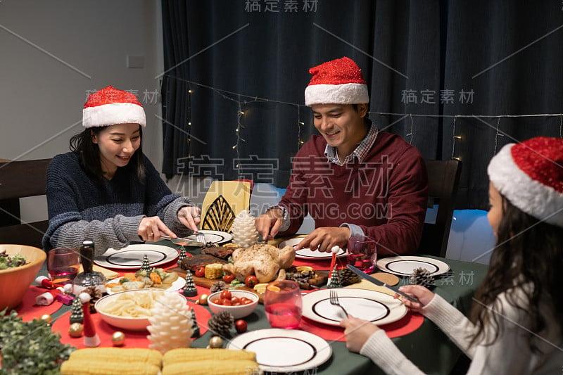 快乐的家庭在圣诞之夜在装饰着圣诞树的餐厅一起庆祝