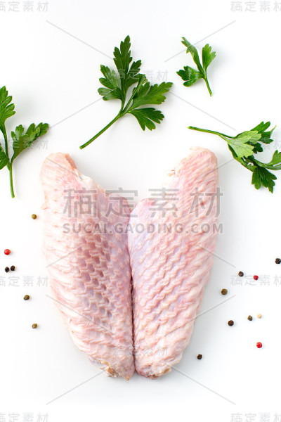白底火鸡生鸡翅配上欧芹和胡椒