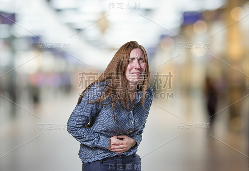 漂亮的年轻快乐的商业女人胃疼痛在模糊的背景