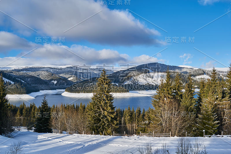 冬季景观从山上有湖，冷杉林，雪和蓝天与云