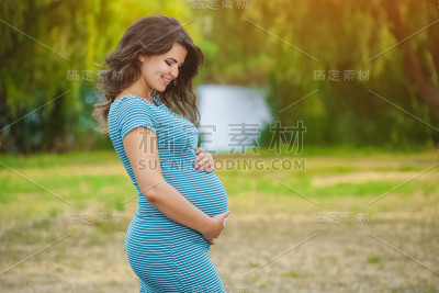美丽的成年孕妇在湖边公园里