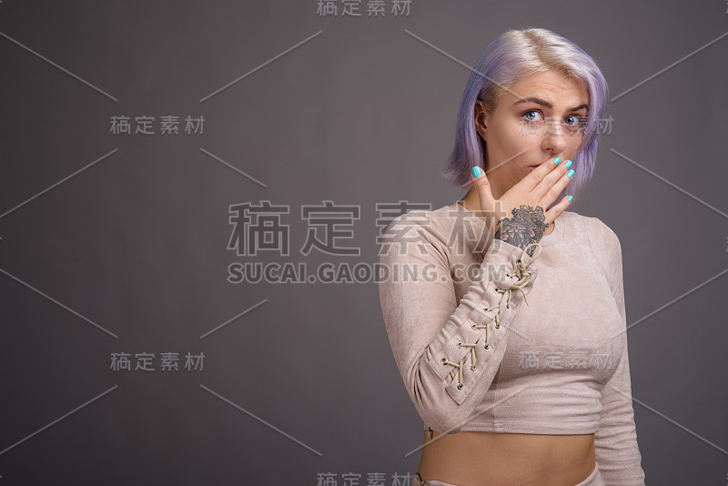 工作室拍摄的年轻美丽的叛逆女子与彩色的头发与灰色的背景