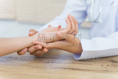 一个医生的近距离握住病人的手做基本的医疗检查和诊断。
