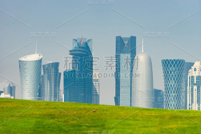 多哈的现代天际线全景与绿色草地前景。健康环境的概念