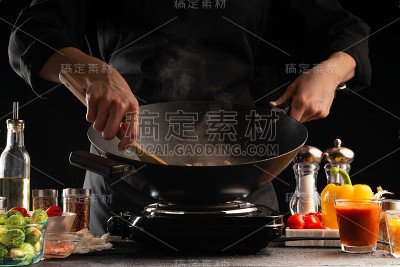 厨师在平底锅中烹煮肉类与蔬菜，以新鲜蔬菜为背景，烹饪食谱。餐饮业务、酒店业务。