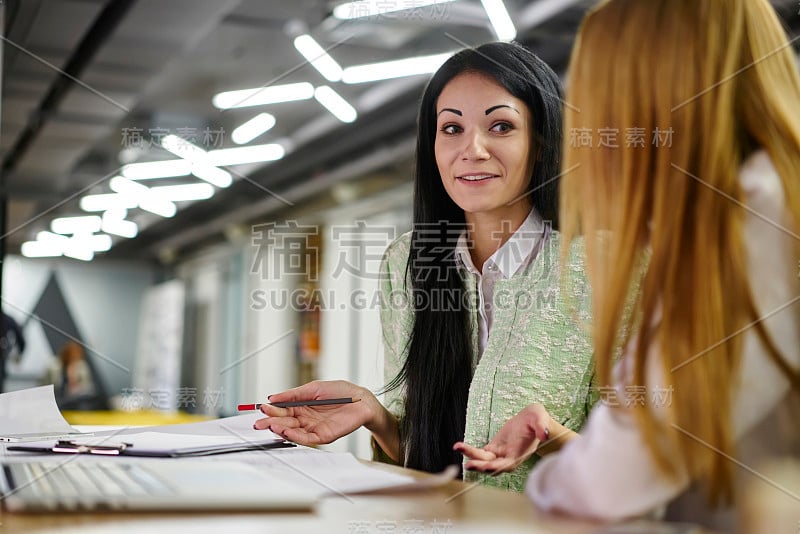 迷人微笑的女商人穿着正式的服装，在时尚的办公室内与同事交流工作过程中的想法。复制空间为您的广告文字信