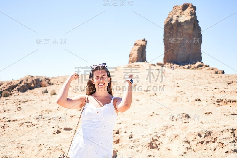 在大加那利岛的罗克努布洛山顶上，年轻美丽的女子在山景上享受暑假，快乐地微笑着庆祝