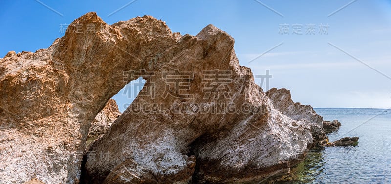 爱琴海夏季海岸上有一个洞的大岩石