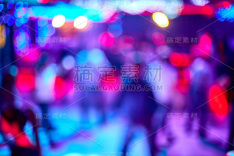 人们跳舞，唱歌，娱乐和放松在夜总会模糊的背景。闪烁的灯光美丽模糊的灯光在舞池放松晚上在俱乐部