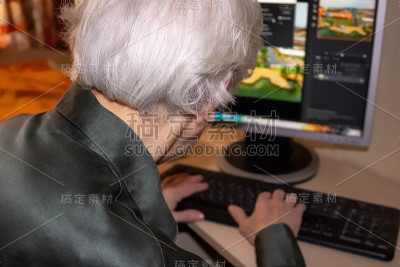 一位老妇人的手正在敲击电脑键盘
