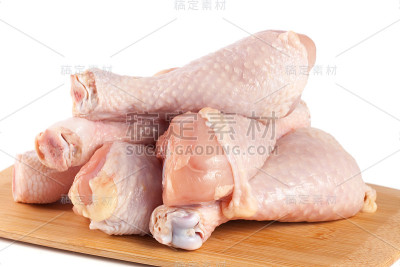 生鸡腿放在木砧板上，白色背景