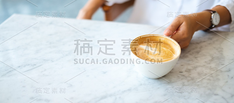 一个女人拿着一杯热咖啡放在桌子上