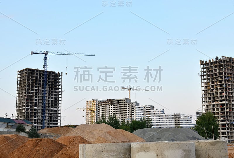 塔吊和新的高层住宅建筑在夕阳背景下的一个巨大的建筑工地。建筑施工，模板和混凝土结构的安装