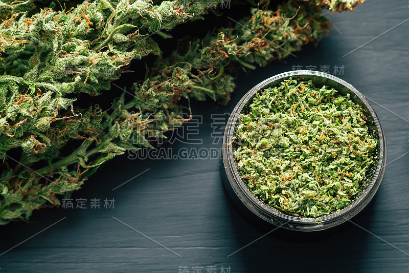 宏观的大麻与毛和粉碎的杂草在一个研磨机切canapis在一个黑色的桌子