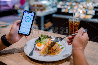 亚洲男人检查他的每日计算和卡路里，而吃午餐。