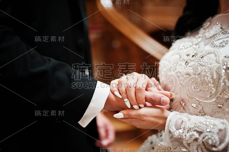 婚礼新人手牵手的特写室内。