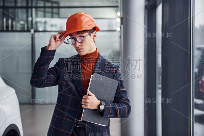 年轻男子的肖像，在保护头盔和正式的衣服，站在室内