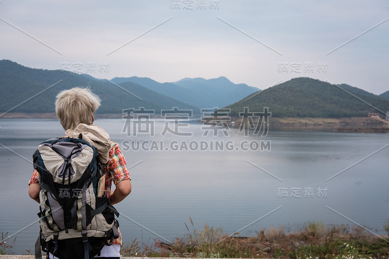 旅行者徒步旅行男子背包徒步附近的湖。旅游背包客在户外放松。旅行的生活方式，暑假的概念