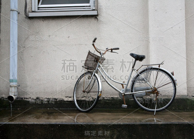 雨中靠墙停放的城市自行车